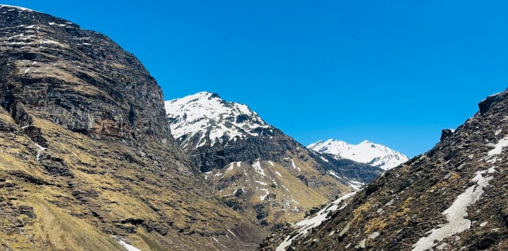 A breathtaking view of snowy mountains and blue skies in Manali, India, during winter.